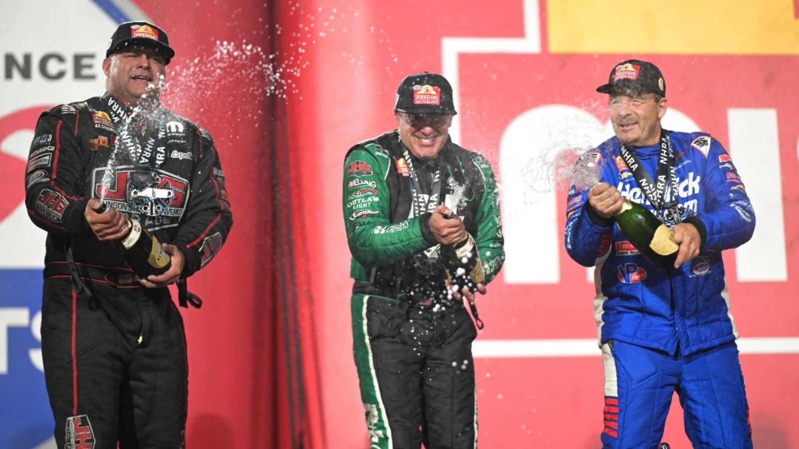 Tony Stewart and fellow racers spraying champagne on the NHRA podium after winning