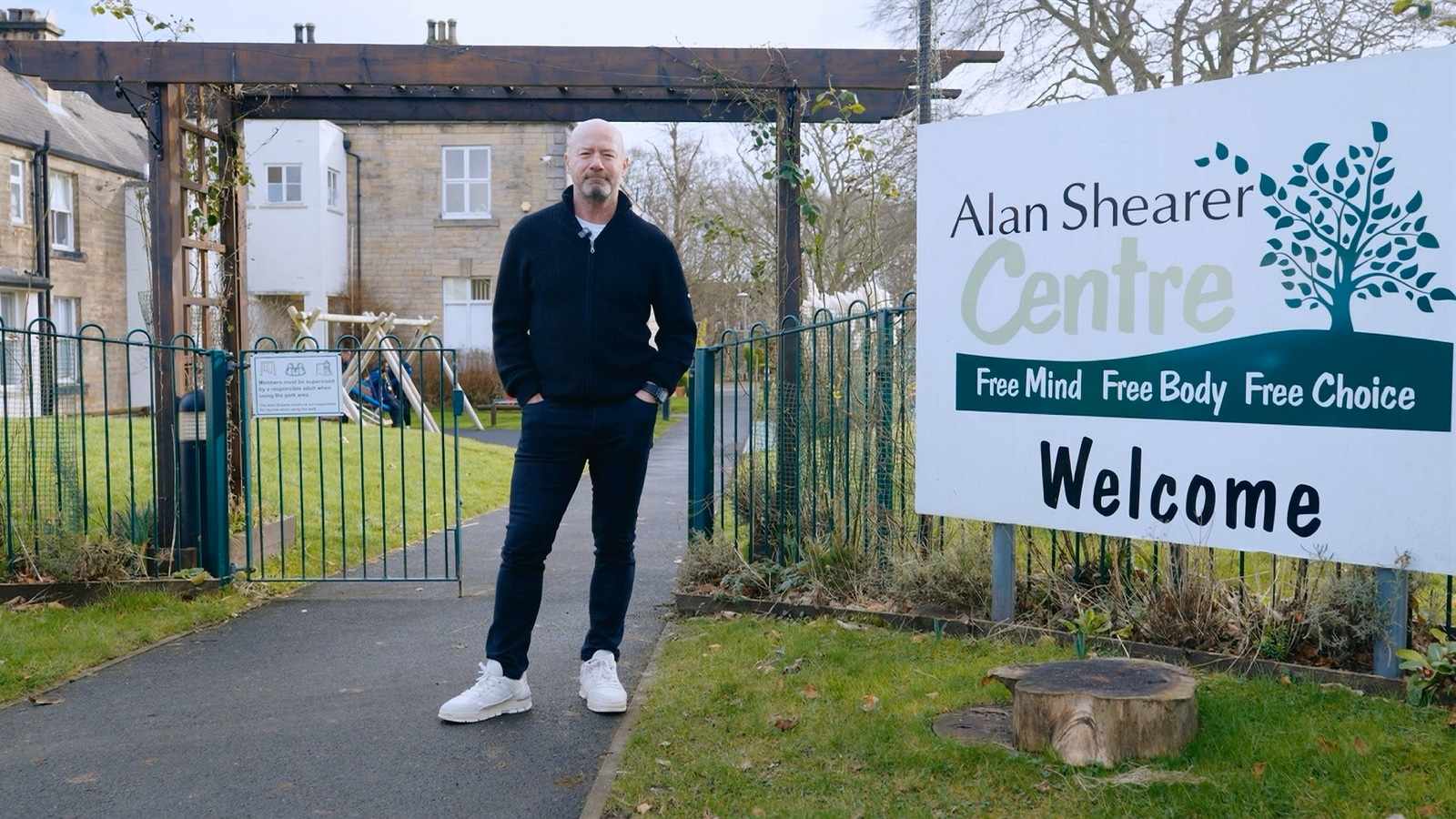 Alan Shearer standing outside the Alan Shearer Centre entrance sign in Newcastle
