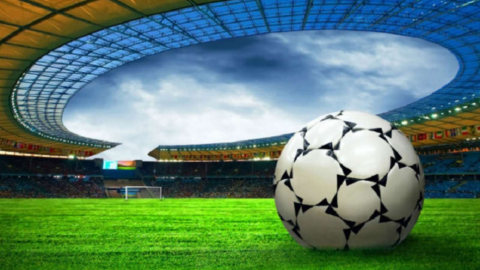 A soccer ball sits on the grass of a large modern stadium field
