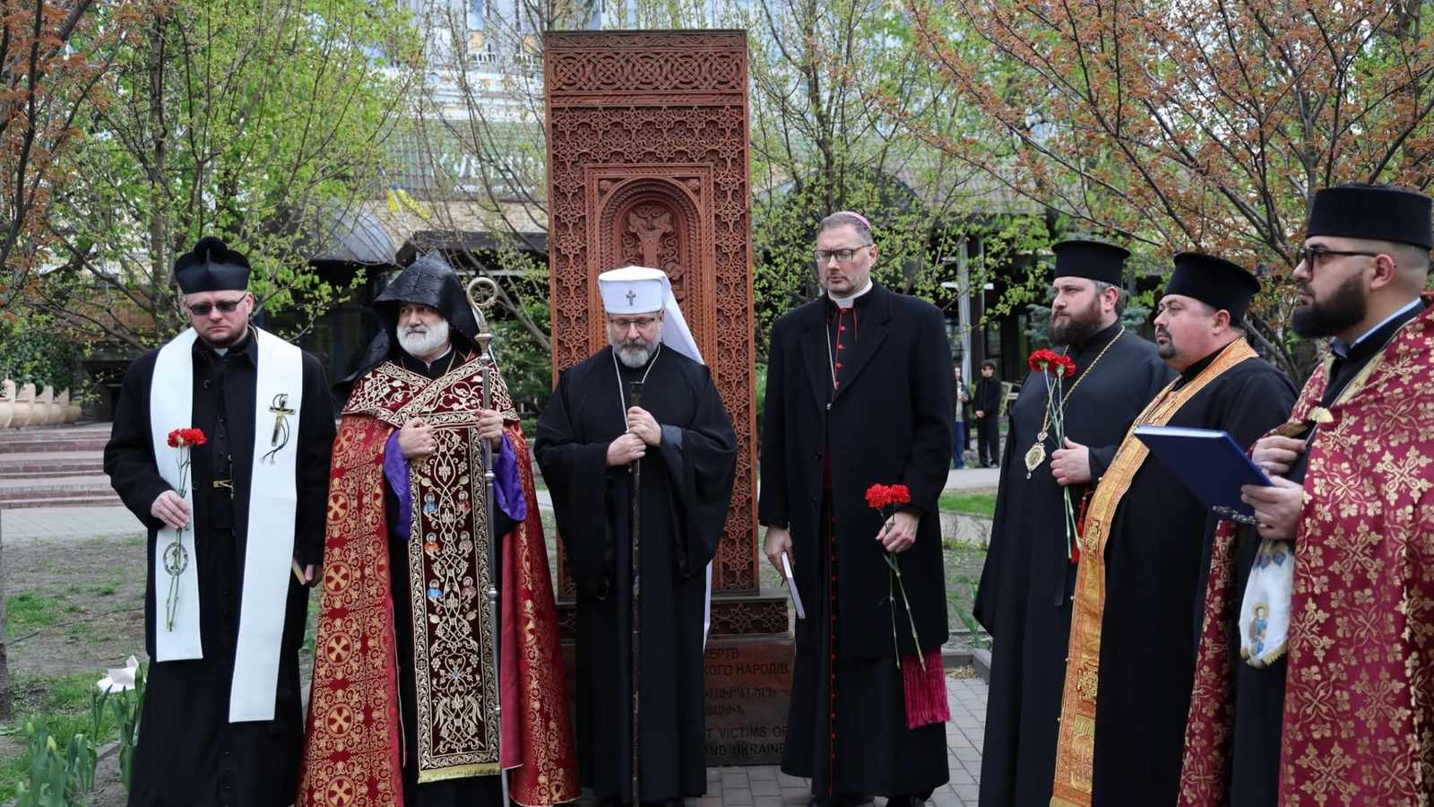 Religious leaders and clergy standing before an Armenian khachkar during a memorial ceremony