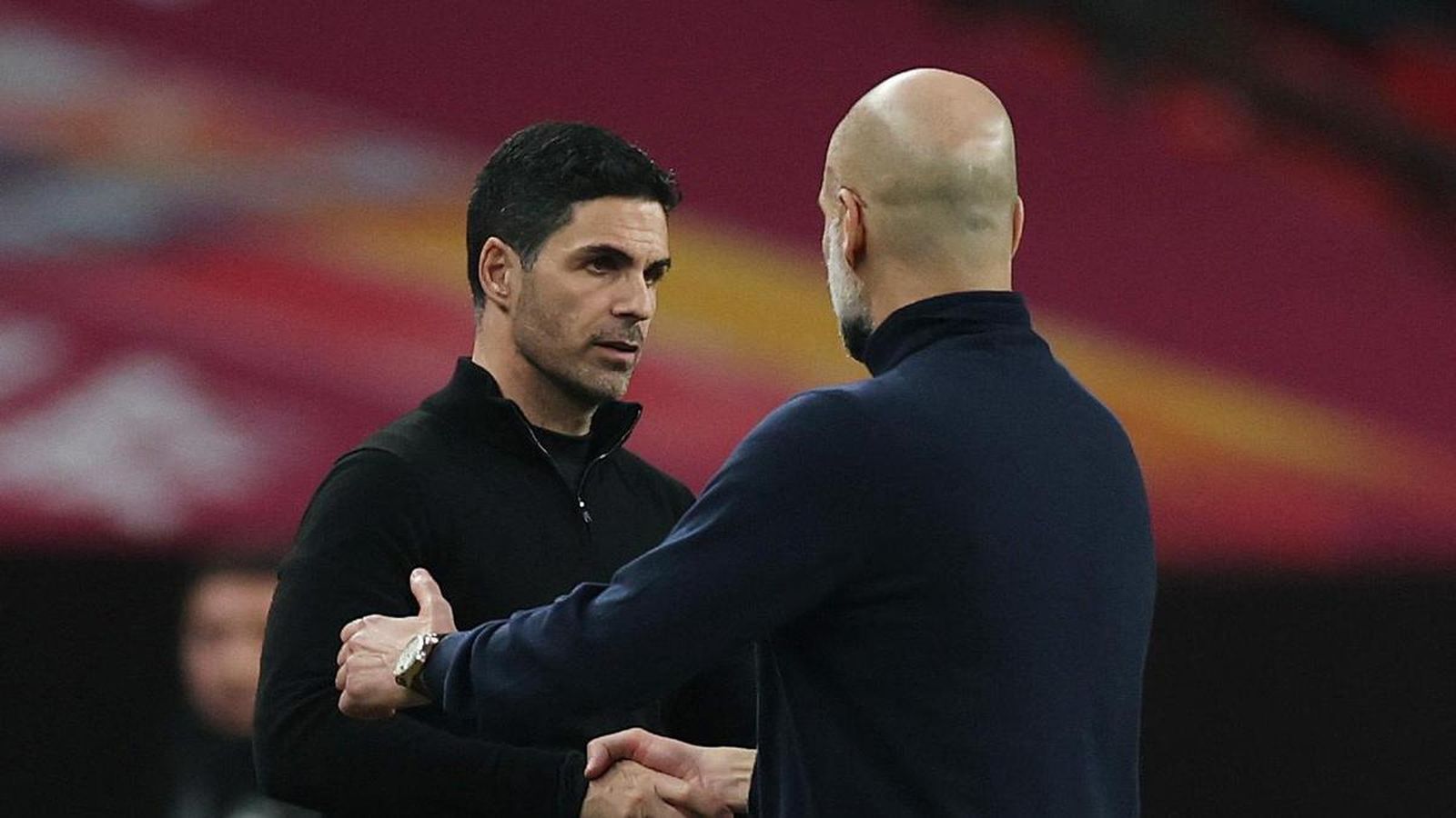 Mikel Arteta and Pep Guardiola shaking hands on the football pitch after a match