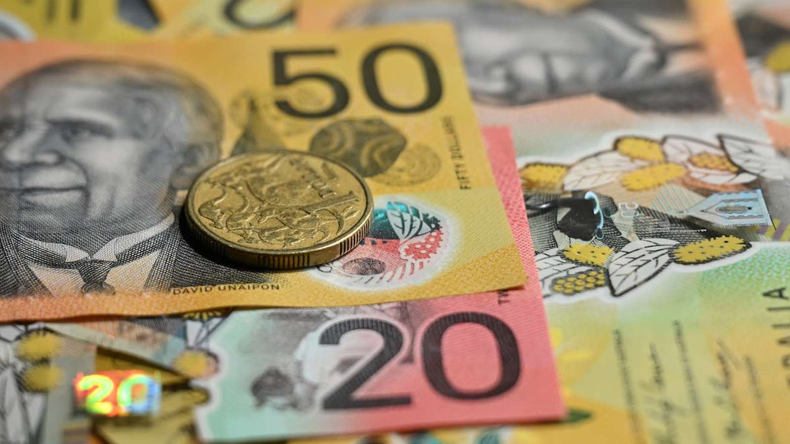 A close-up view of Australian fifty and twenty dollar banknotes with a gold coin.