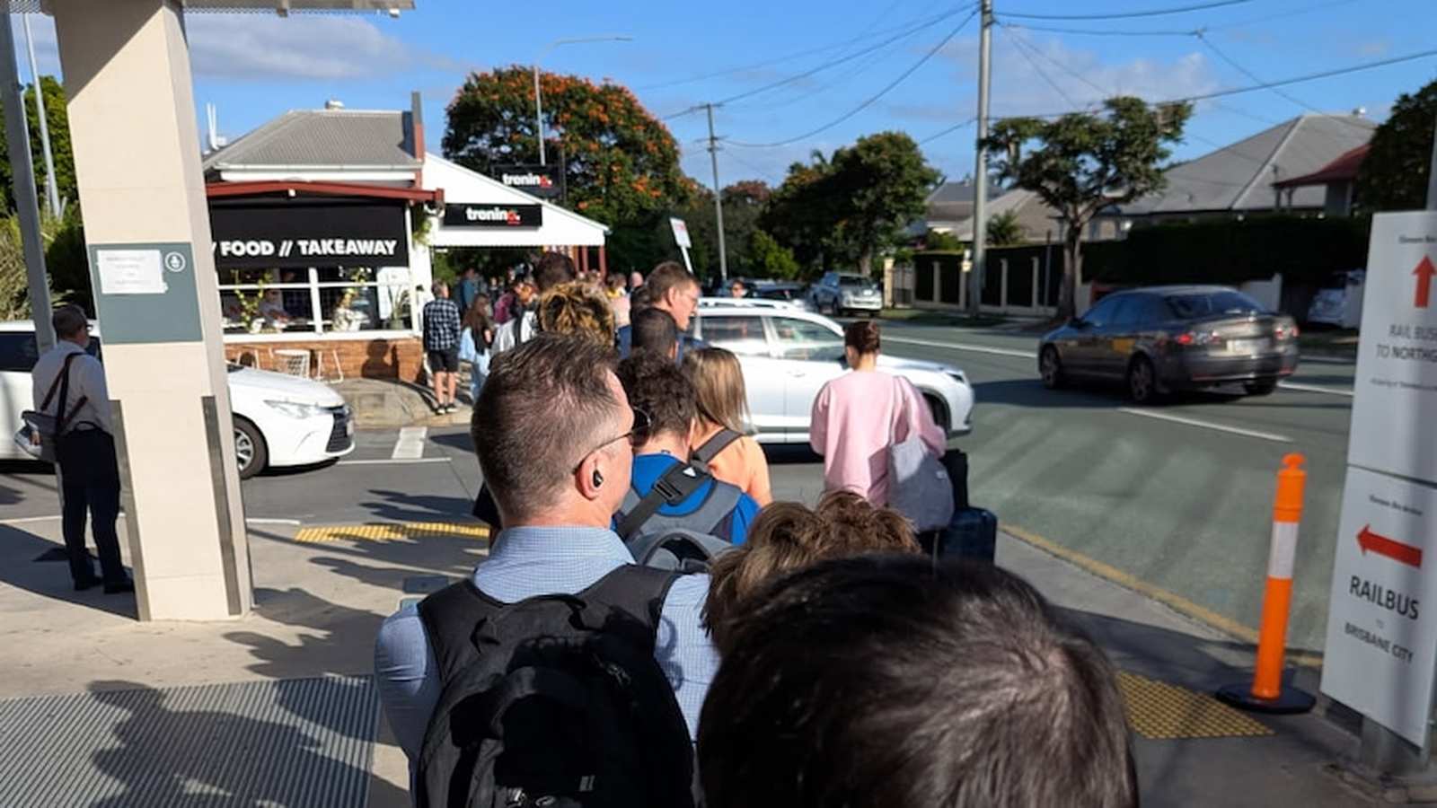 A long line of commuters waiting at a bus stop in Brisbane