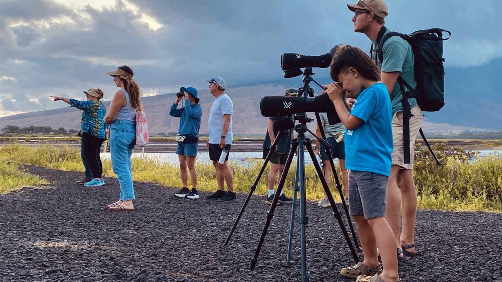 A group of people using spotting scopes to observe wildlife in a wetland