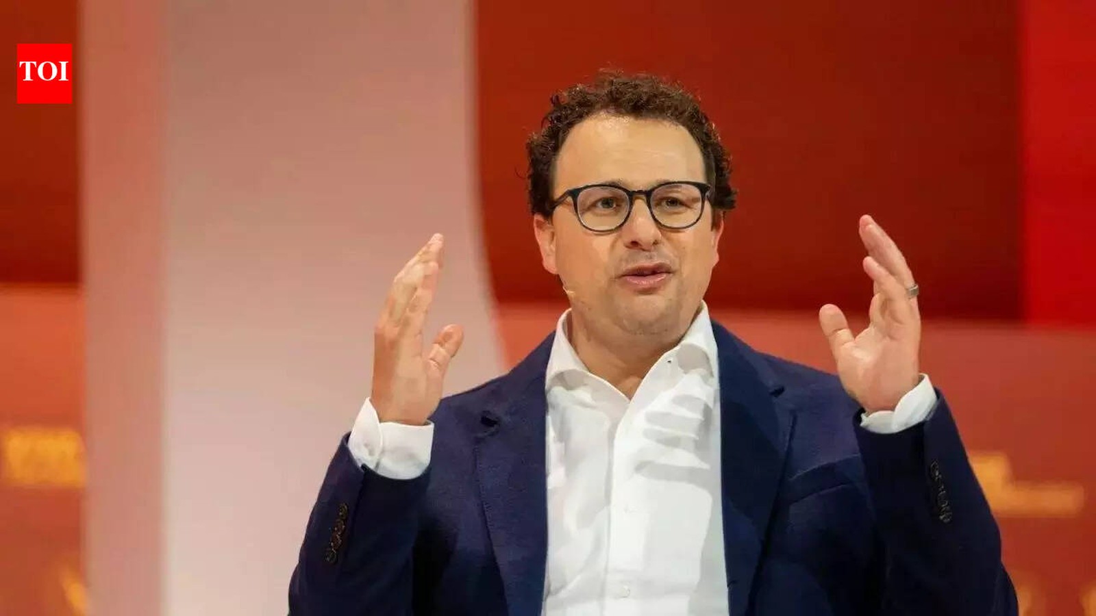 Anthropic CEO Dario Amodei speaking on stage with hands raised during a presentation