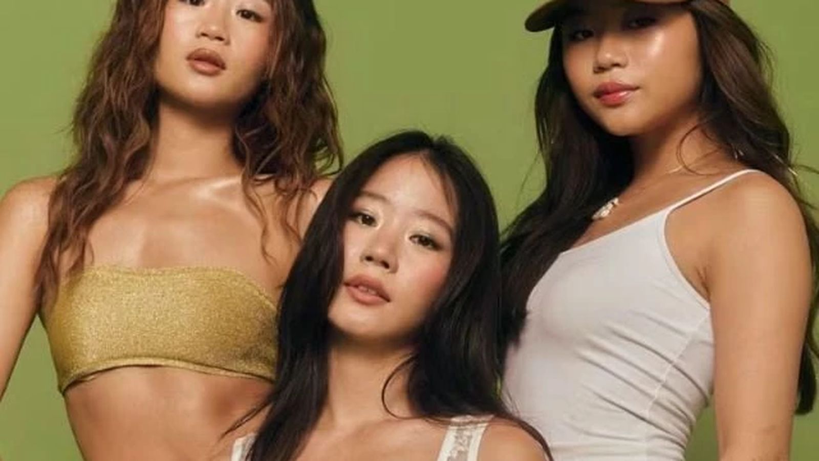 Evelyn Ha posing with two other young women against a solid green background