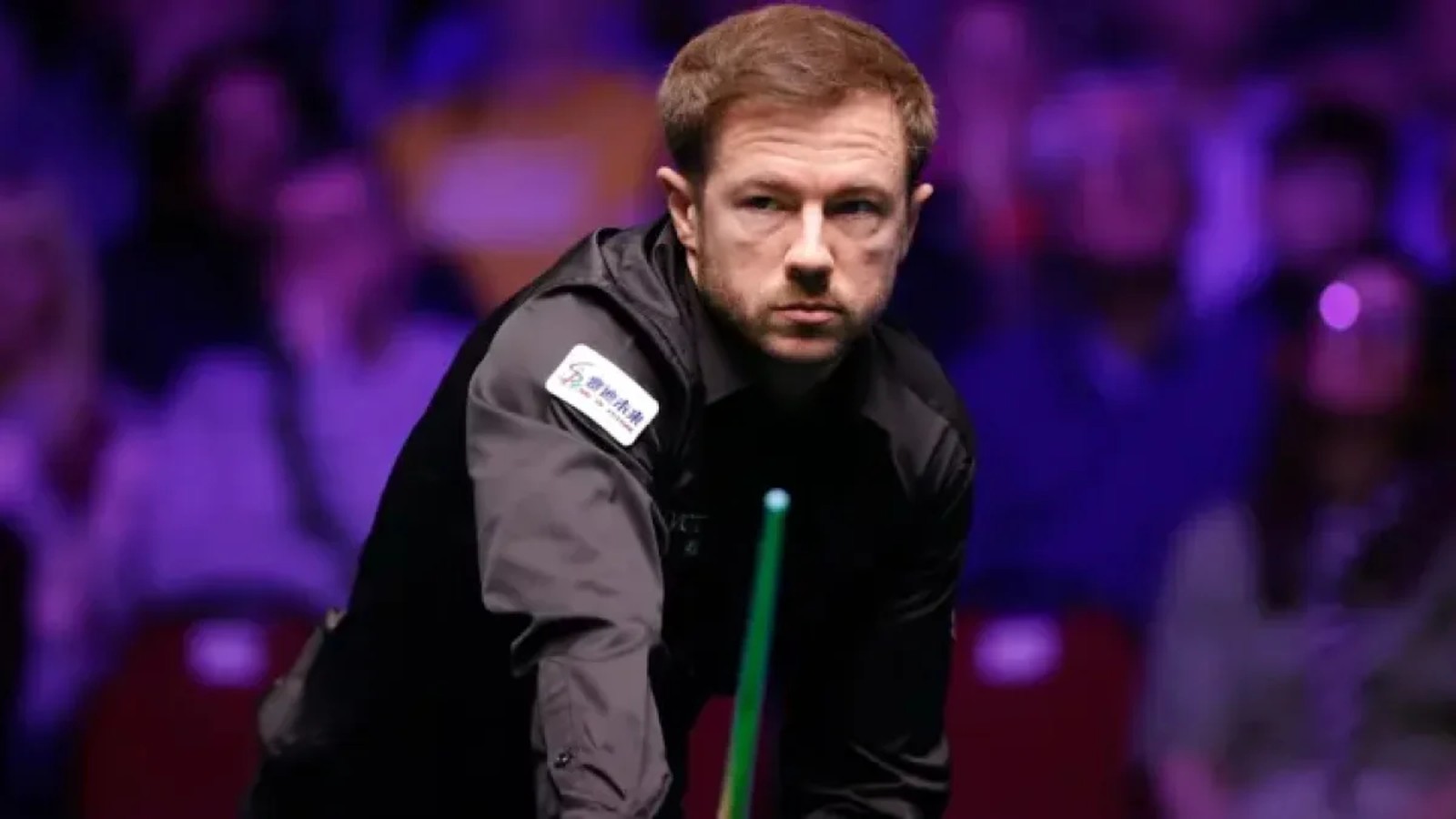 Professional snooker player Jack Lisowski looking focused while holding a cue at a tournament