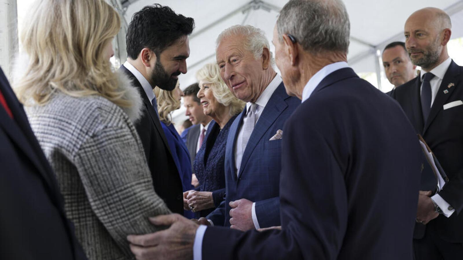 King Charles III and Queen Camilla speaking with officials at a formal event