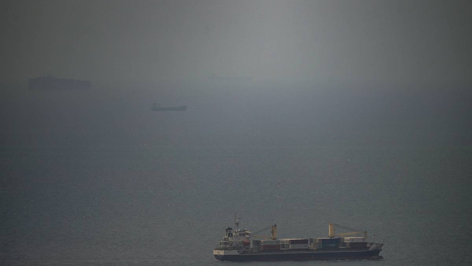 Cargo ships navigating through hazy waters in the Strait of Hormuz region