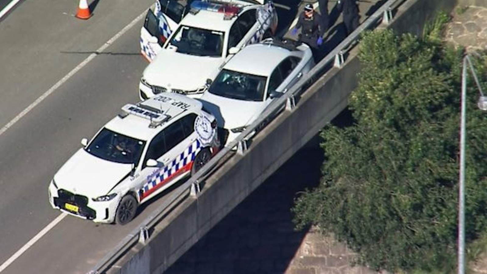 Aerial view of police officers inspecting vehicles stopped on a highway bridge