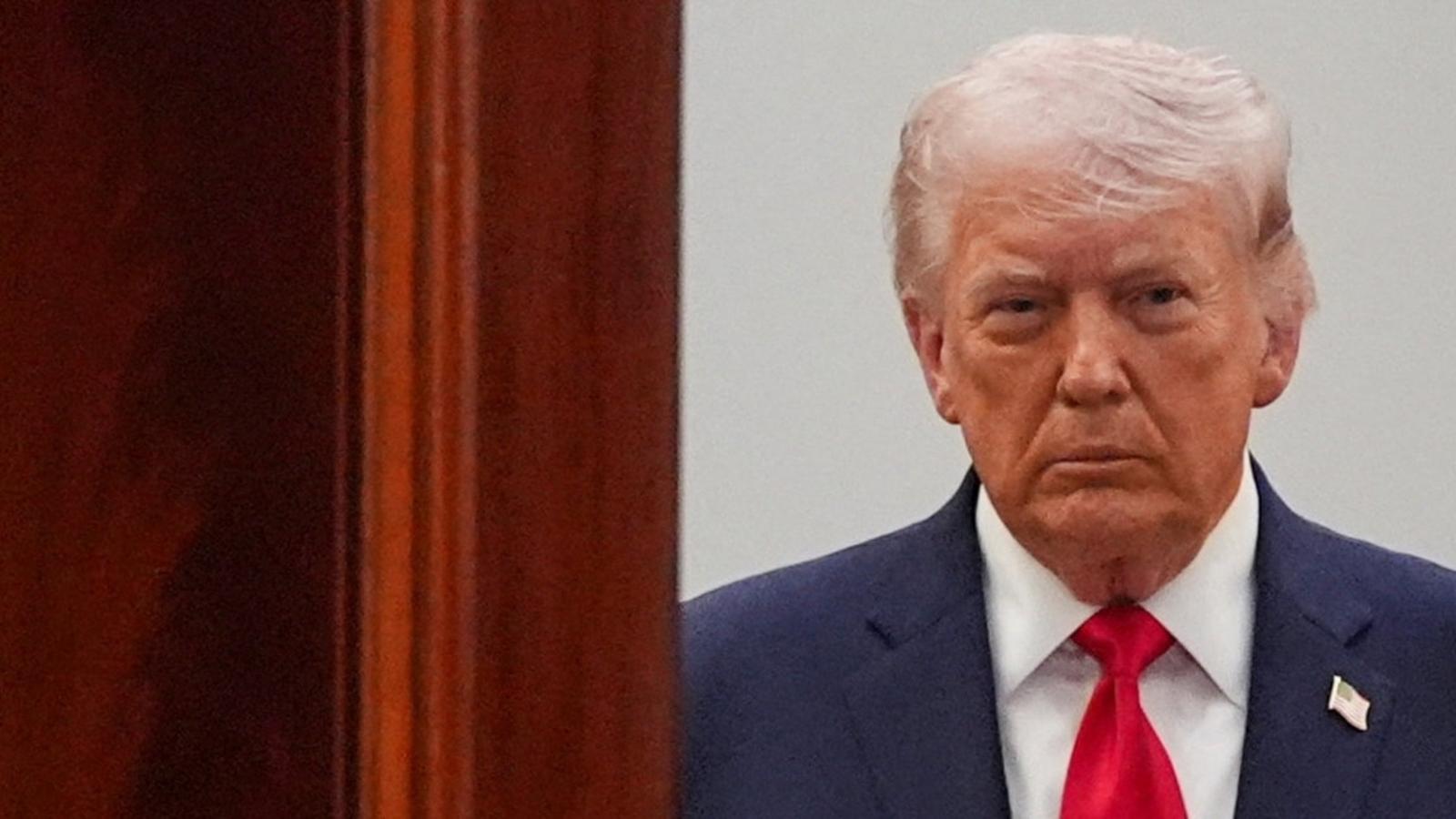 Donald Trump wearing a blue suit and red tie looking directly at camera