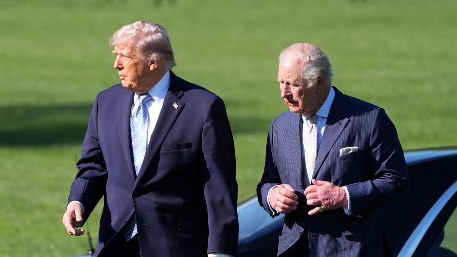 Donald Trump and King Charles III walking together on a green lawn outdoors