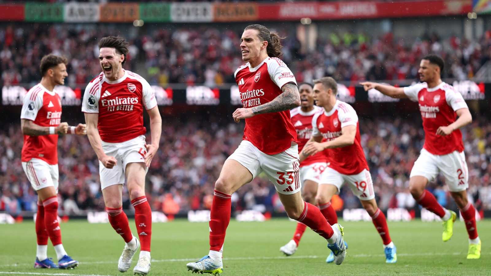 Arsenal football players in red kits celebrating on pitch during a Premier League match