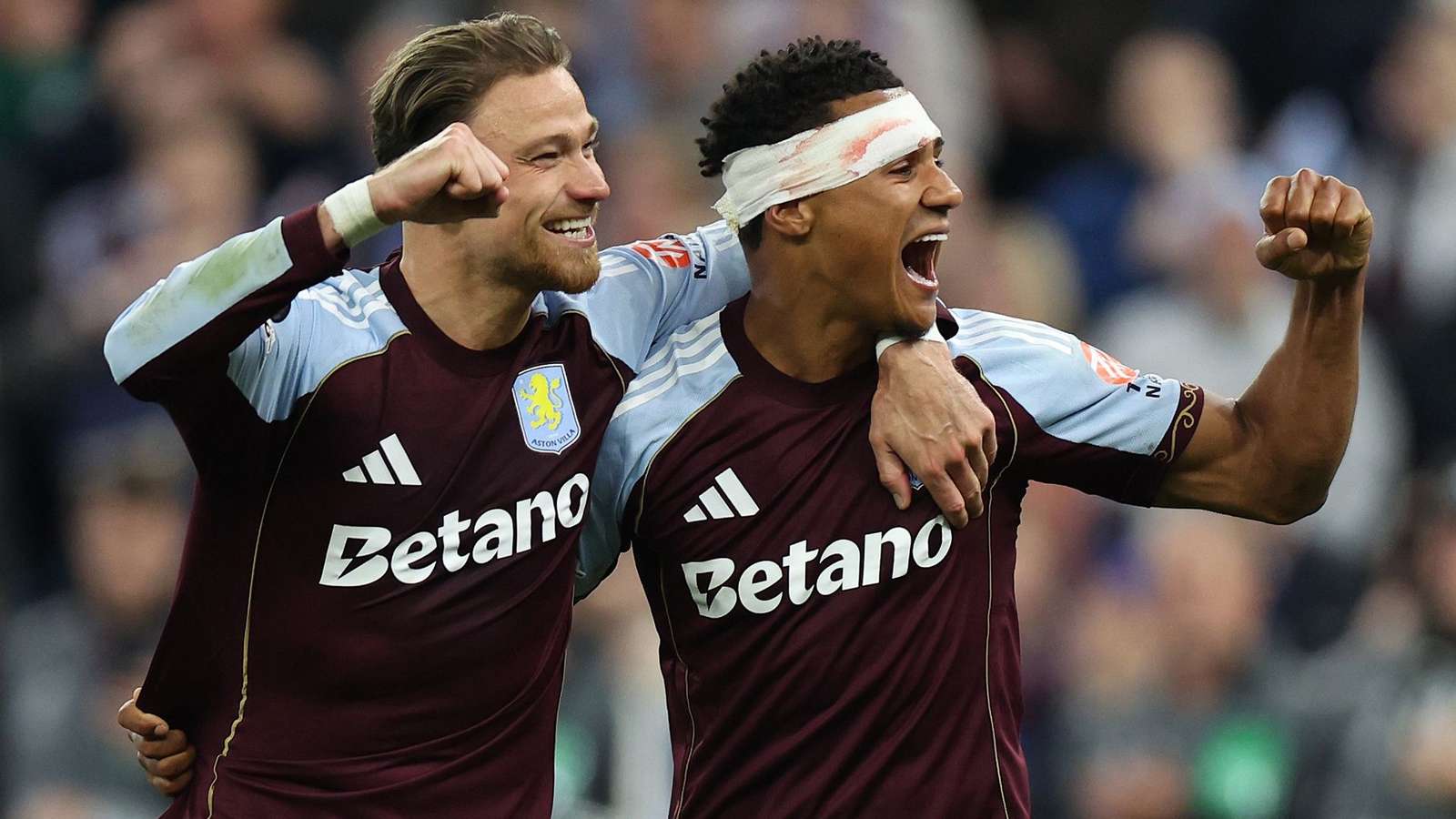 Two Aston Villa players in maroon and blue kits celebrating a goal together