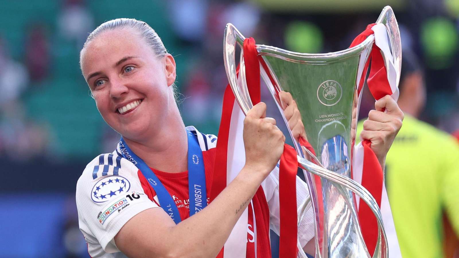 Beth Mead smiling while holding the UEFA Womens Champions League trophy after a match