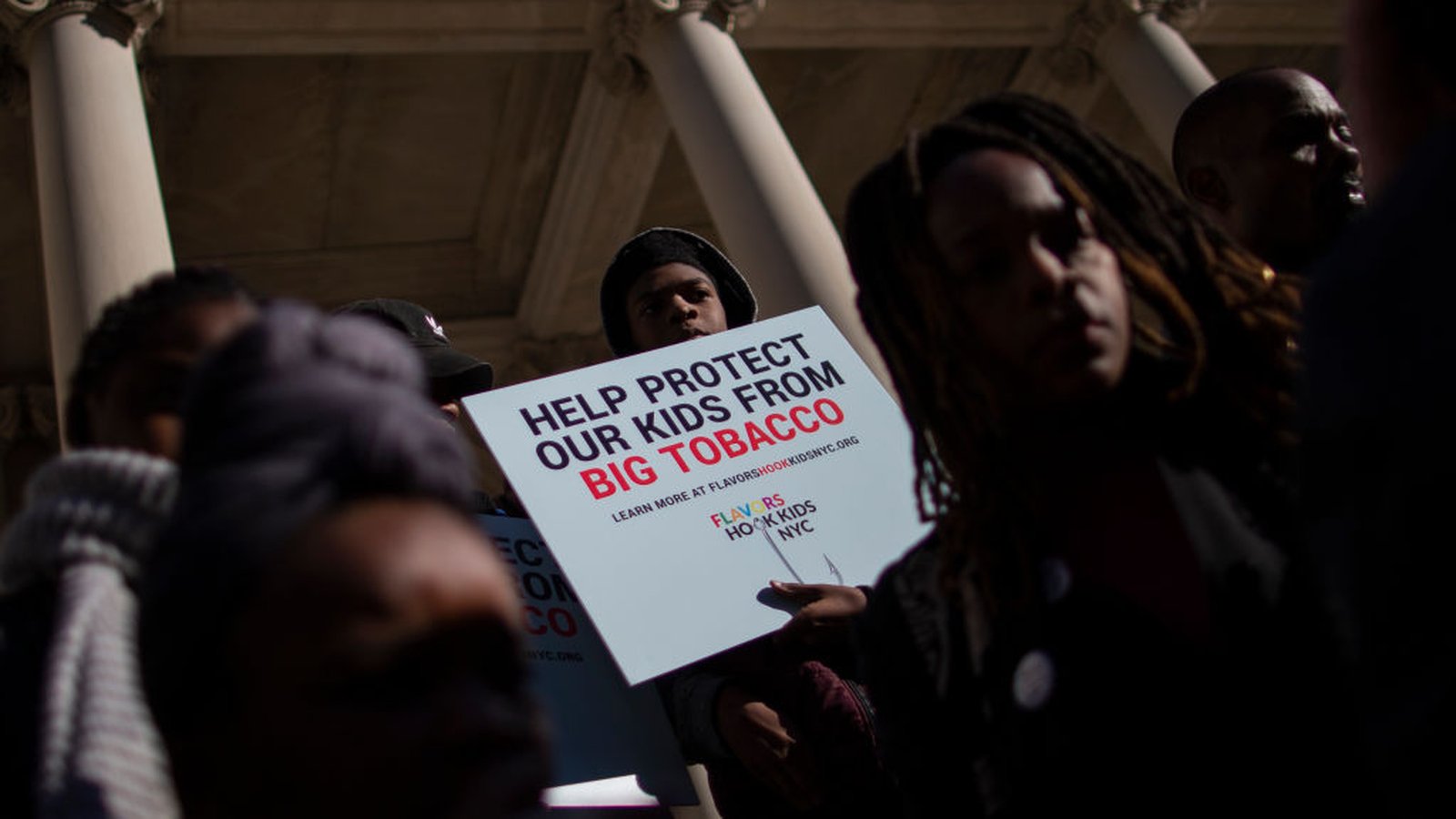 A protester holds a sign reading Help Protect Our Kids From Big Tobacco at a rally