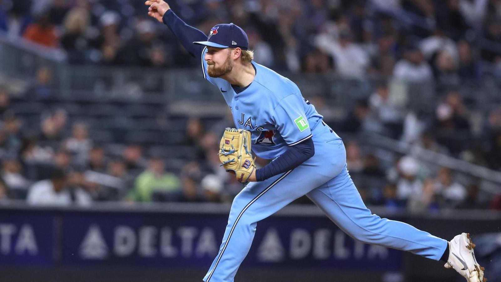 A Toronto Blue Jays pitcher in a light blue uniform throwing a baseball