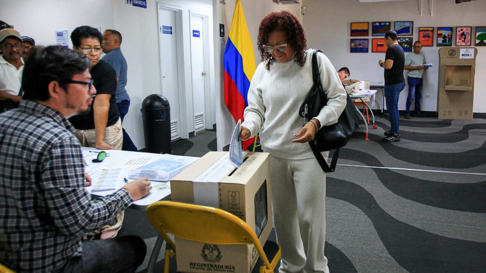 A woman in a white sweater casts her vote at a Colombian polling station