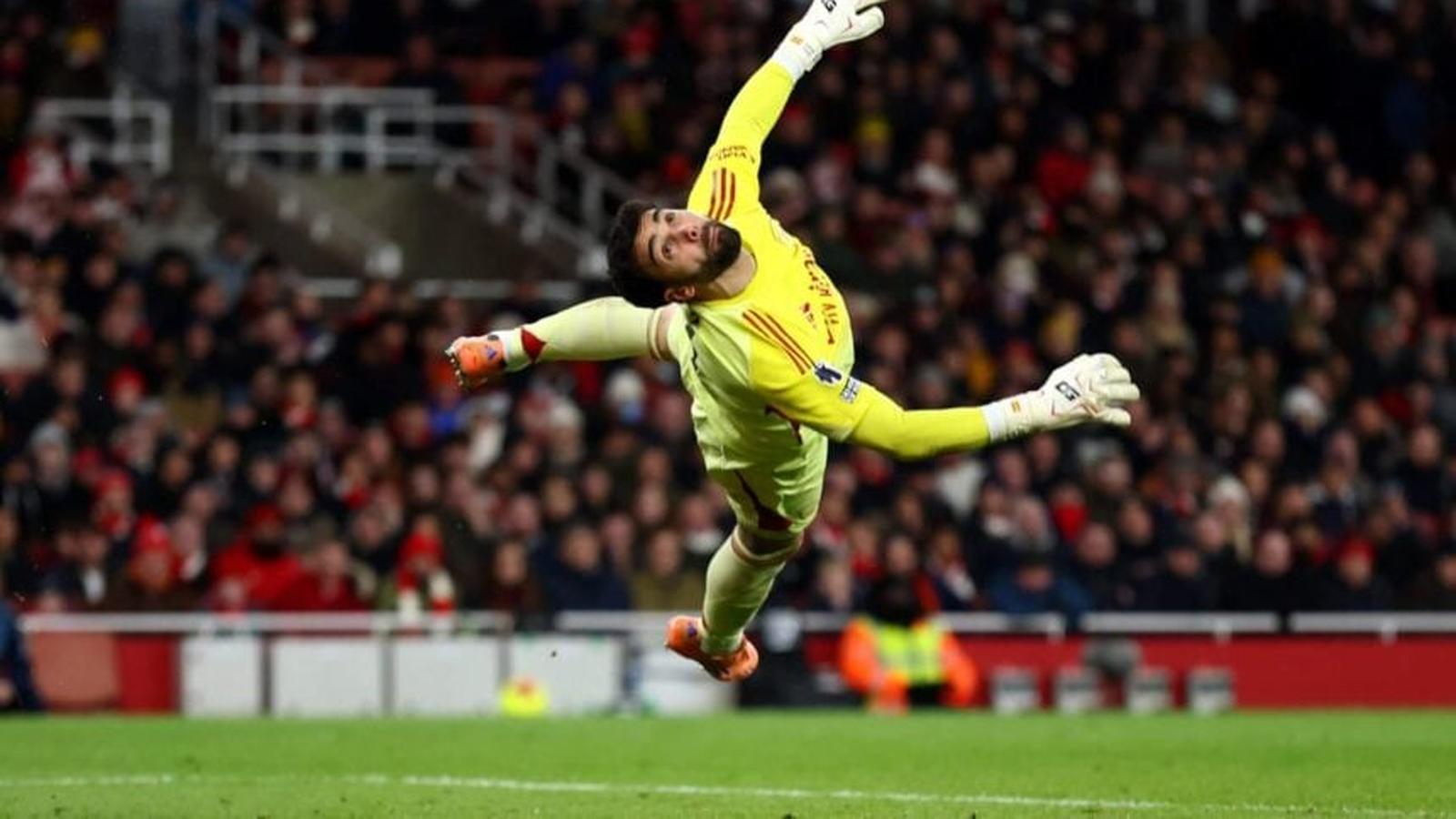 Arsenal goalkeeper David Raya in mid-air, diving to make a save during a football match