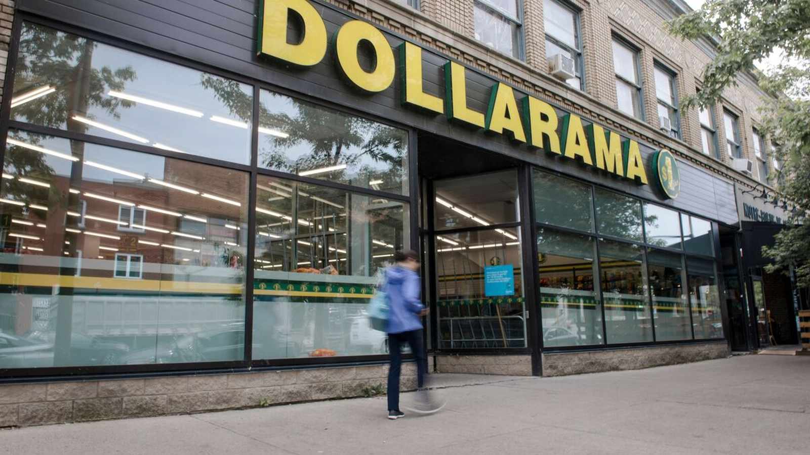 A pedestrian walks past the exterior of a Dollarama retail store in Canada