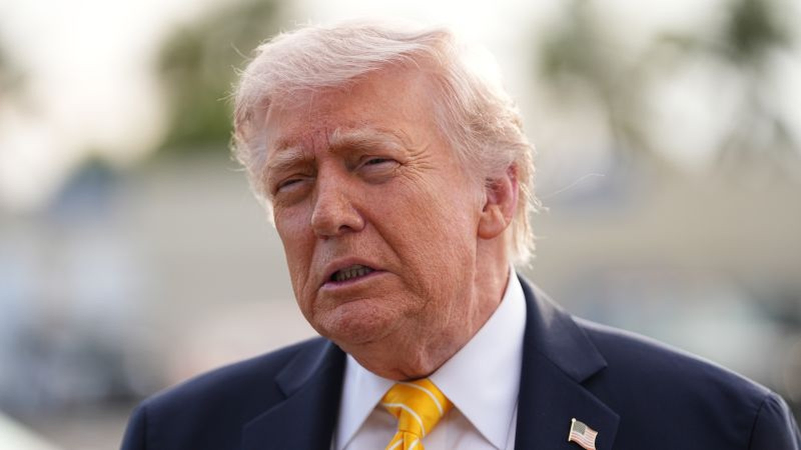 Donald Trump speaking during a press conference with a serious facial expression