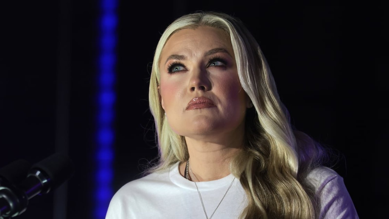 Erika Kirk with blonde hair looking upward during a public speaking event