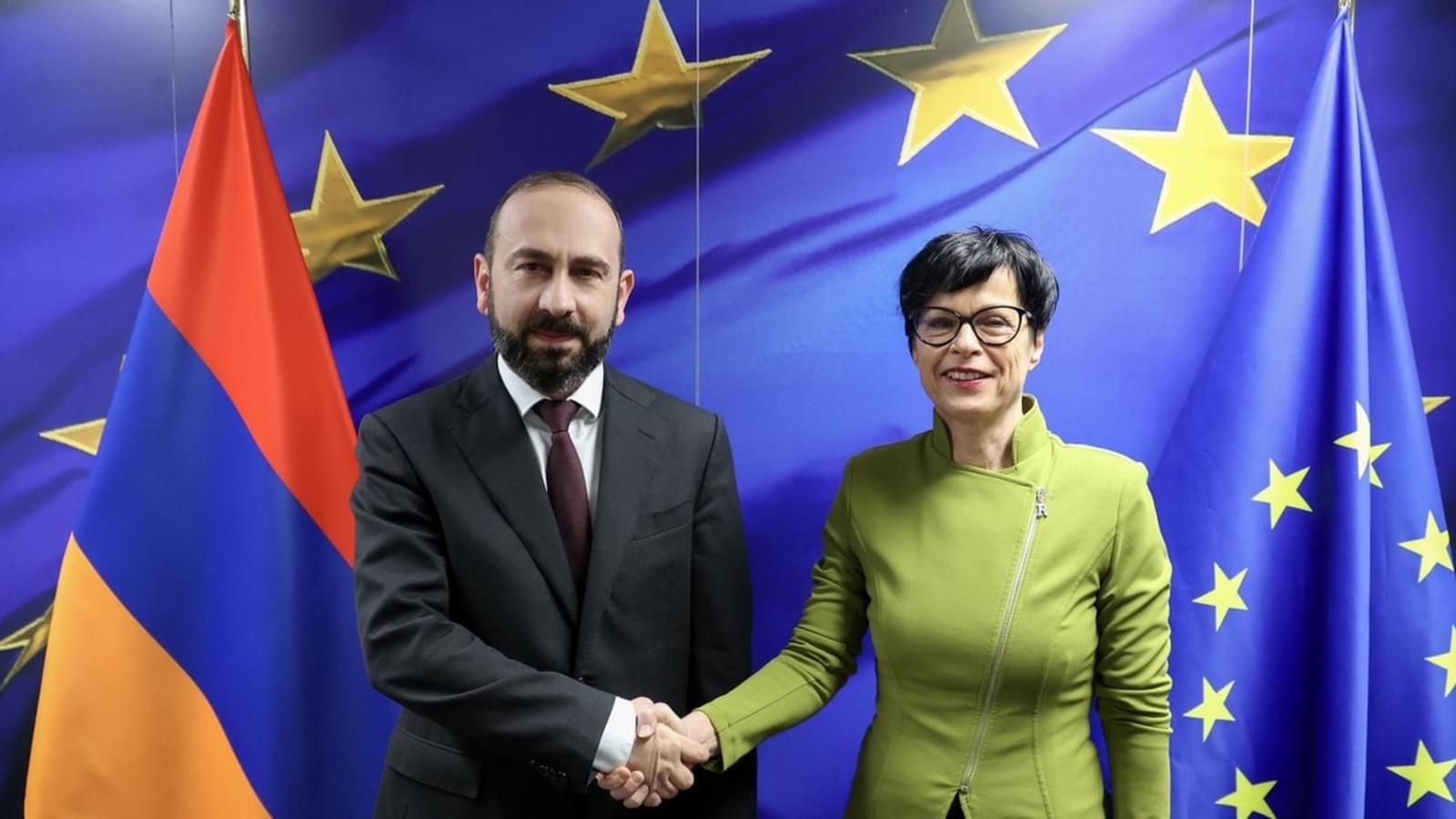 Ararat Mirzoyan and Miriam Lexmann shaking hands in front of Armenian and EU flags