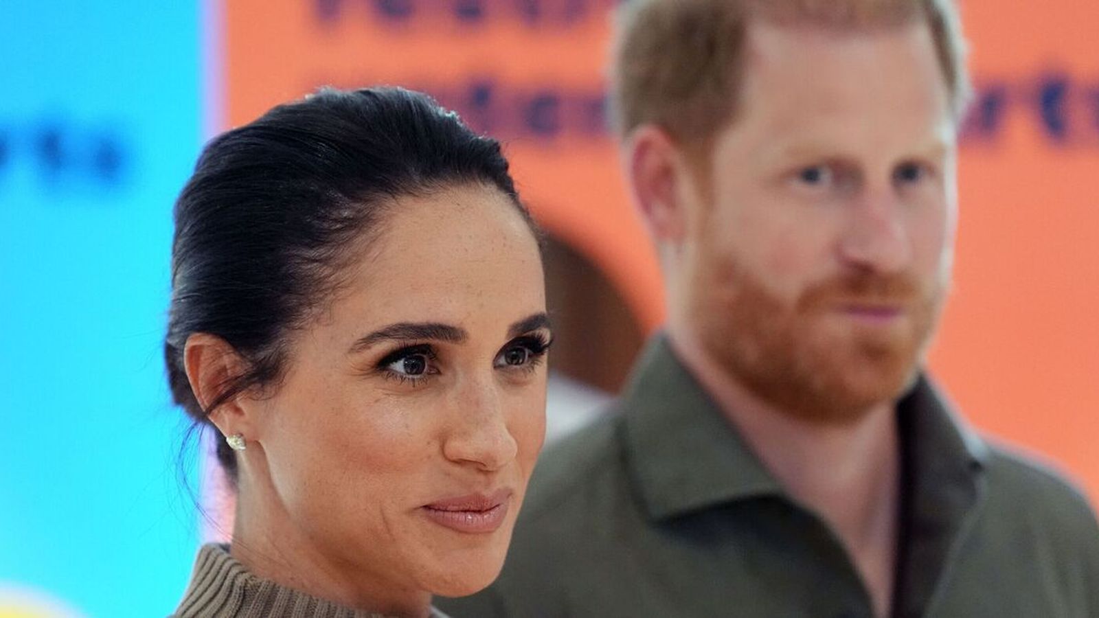 Meghan Markle in the foreground with Prince Harry slightly out of focus behind her