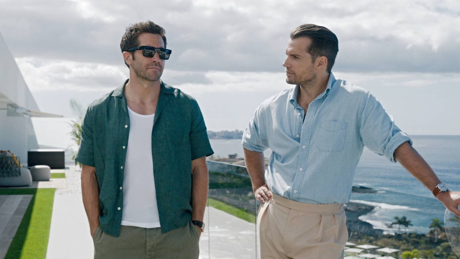 Henry Cavill and Jake Gyllenhaal standing on a balcony overlooking the ocean