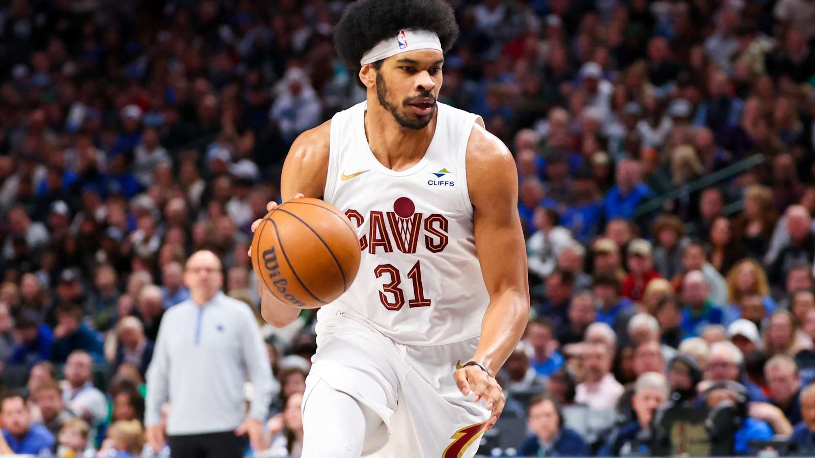 Jarrett Allen wearing a white Cleveland Cavaliers jersey dribbling a basketball on court