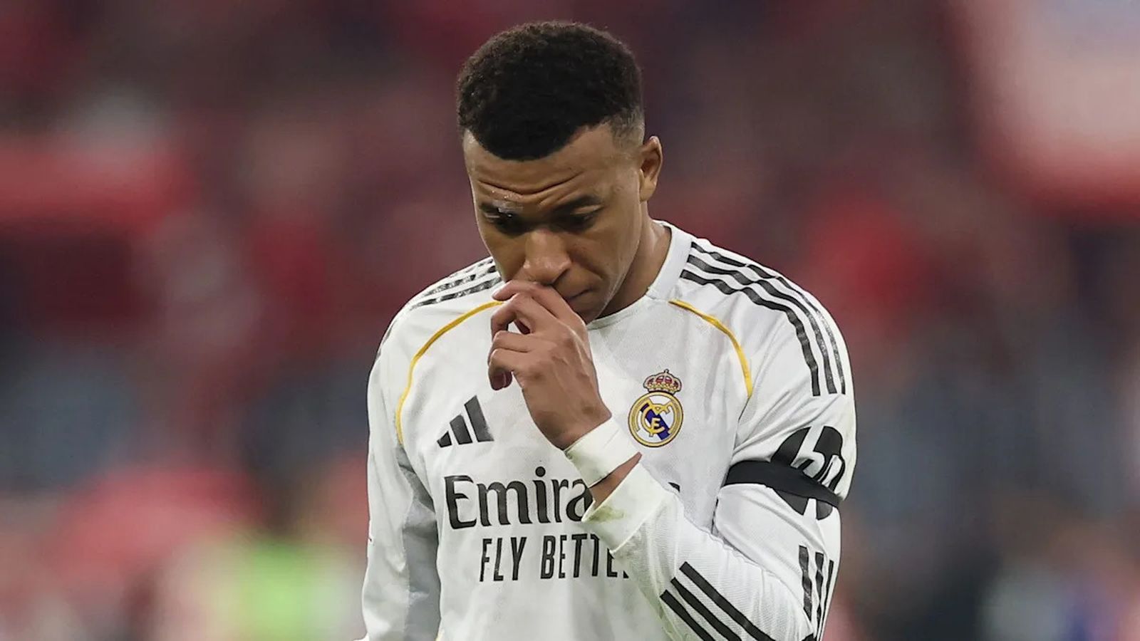 Football player Kylian Mbappe wearing a white Real Madrid jersey with black stripes and gold trim, l