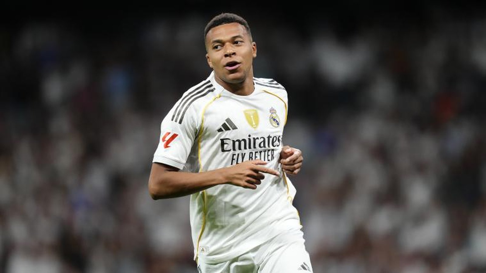 Kylian Mbappe, a young Black man, wearing a white Real Madrid soccer jersey, looking right