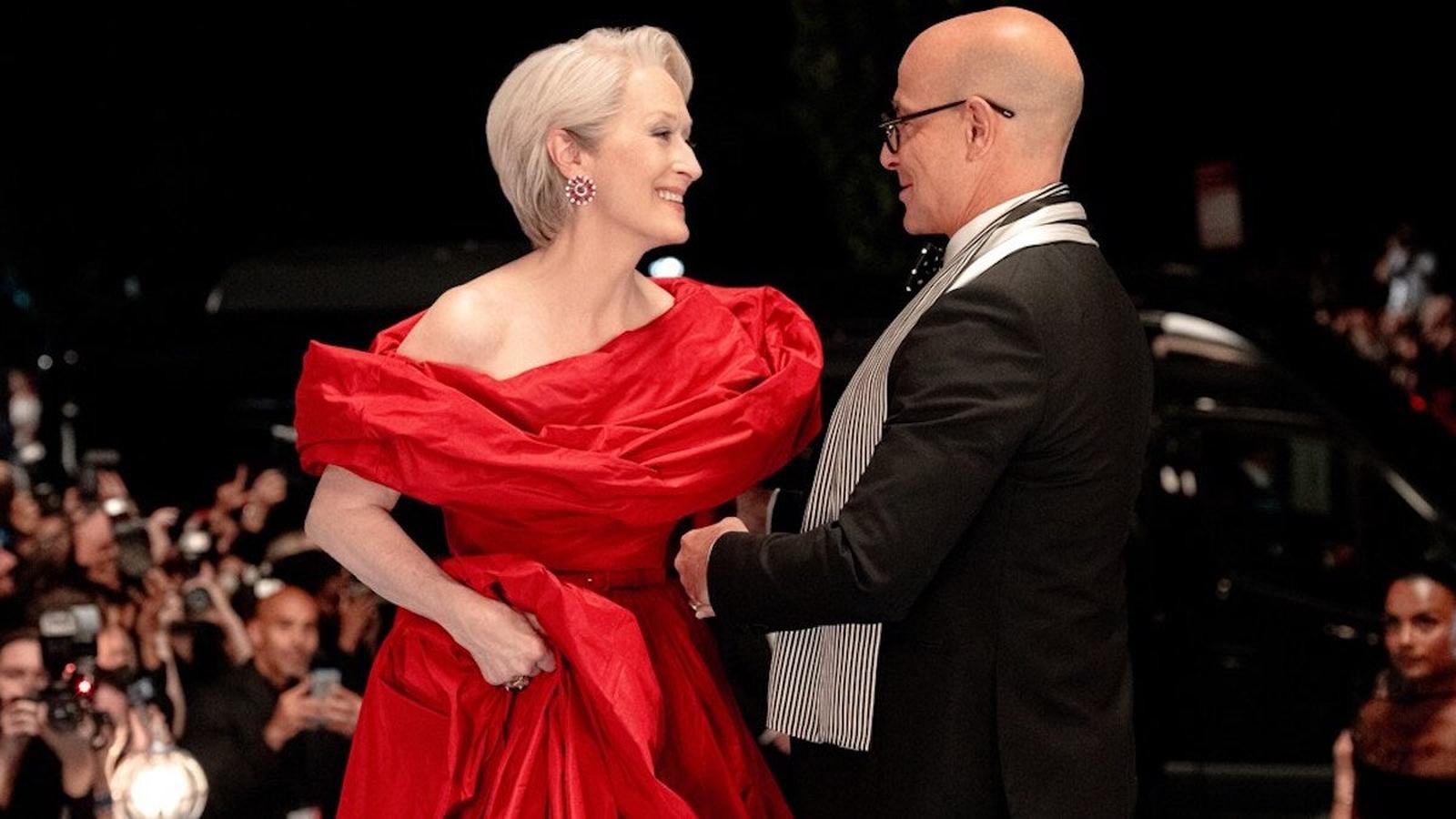 Meryl Streep in a red gown smiling at Stanley Tucci on red carpet