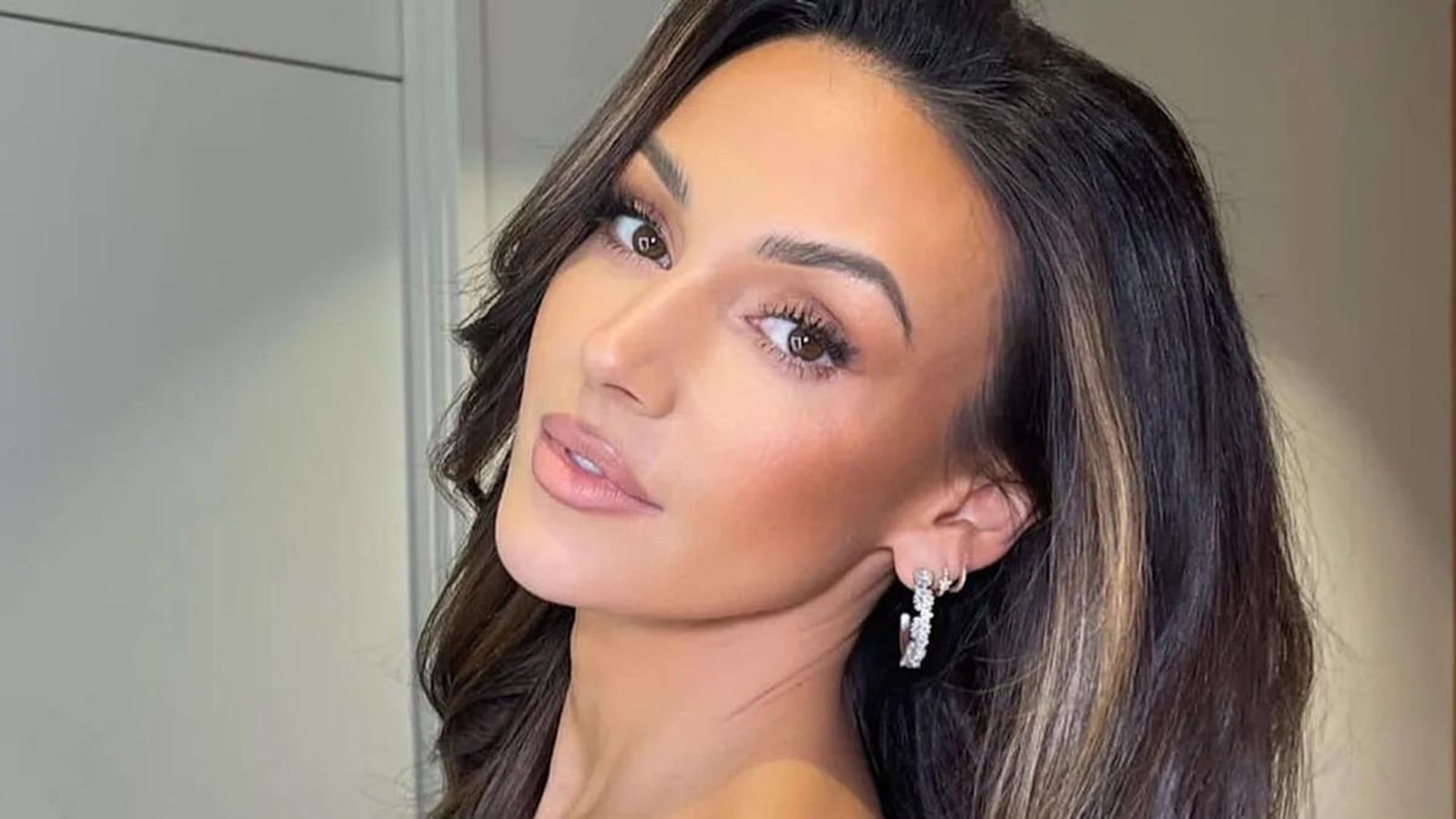 Close up portrait of actress Michelle Keegan with long dark hair and makeup