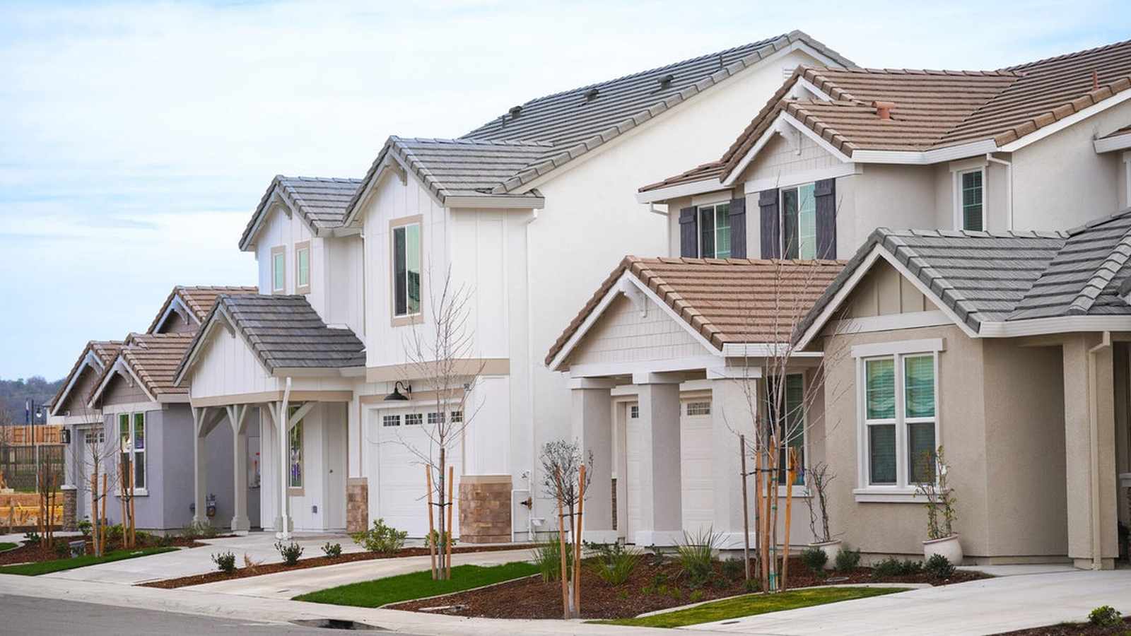A row of modern suburban houses with tiled roofs and neutral colored siding