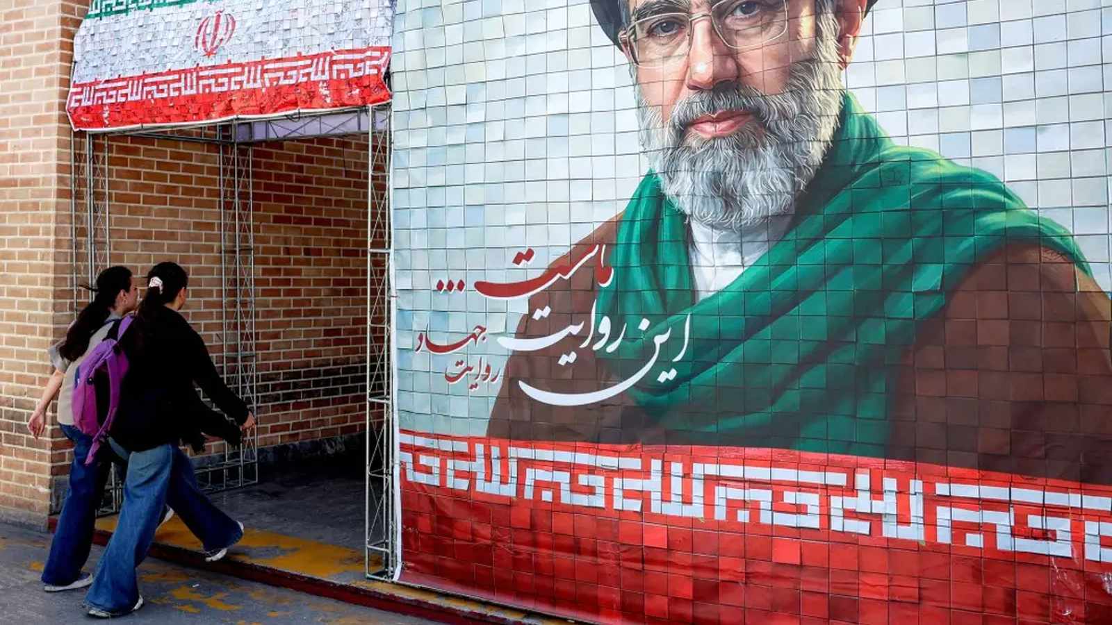 A large mural of Mojtaba Khamenei, wearing a black turban and green scarf, with Iranian flag motifs