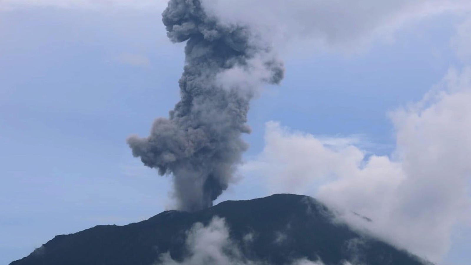 Mount Dukono erupting with a large plume of dark ash and smoke rising into the sky