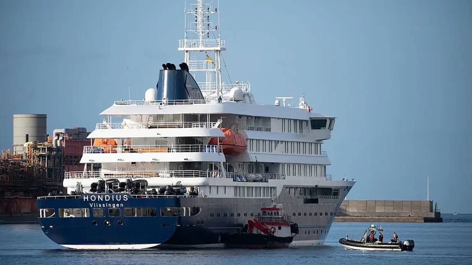 The cruise ship MV Hondius docked in a harbor with a small boat nearby