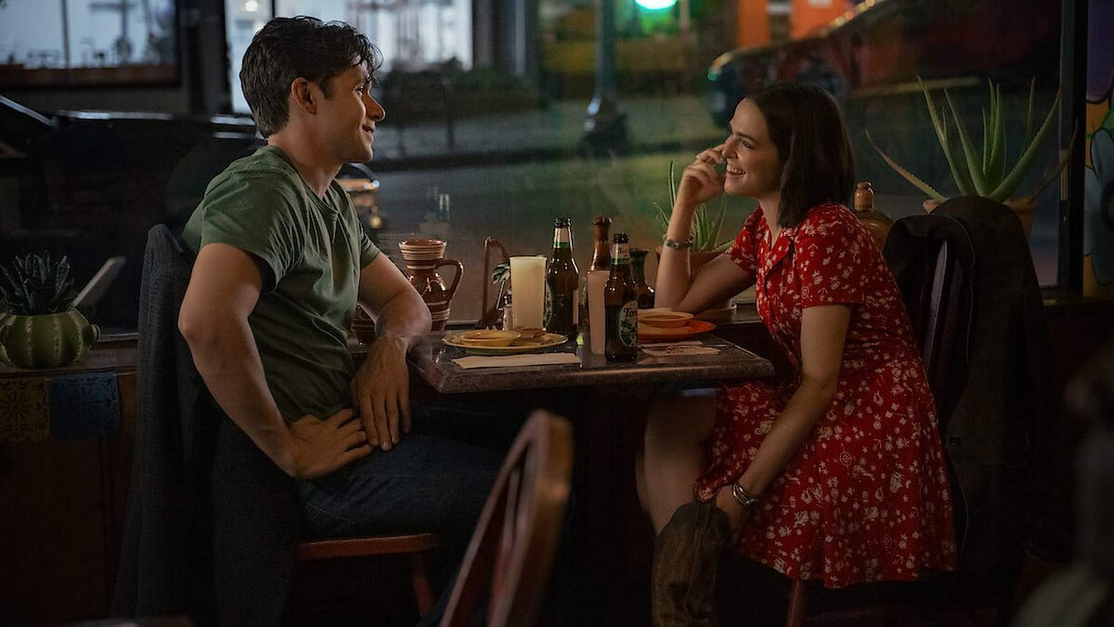 Nick Robinson and Zoey Deutch smiling at each other during a romantic dinner date