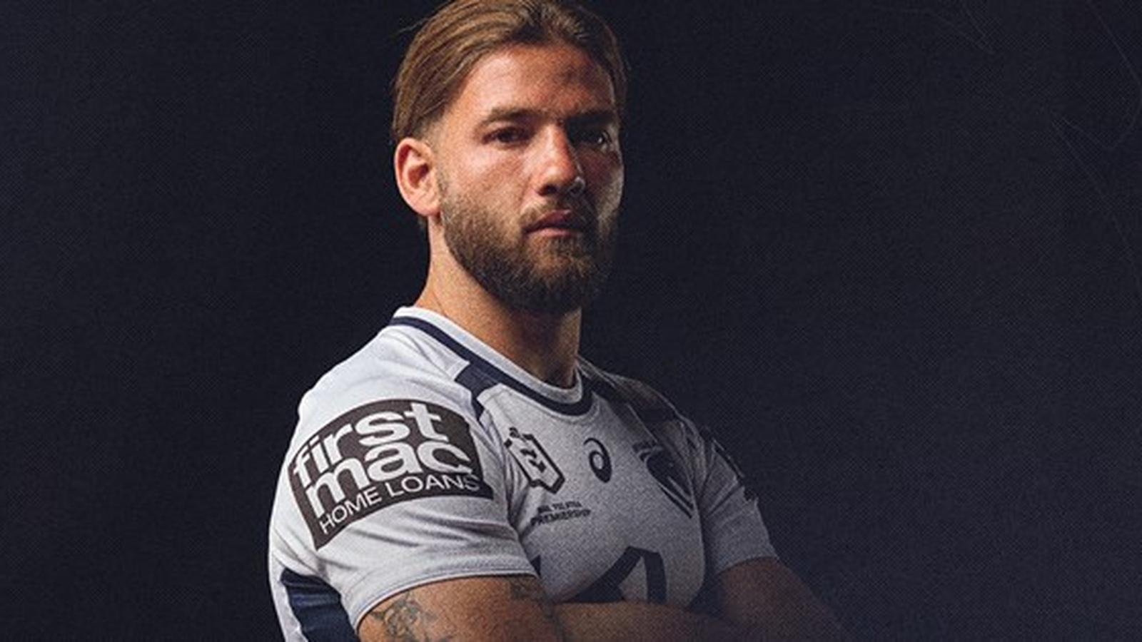 A professional rugby league player wearing a team jersey against a dark background