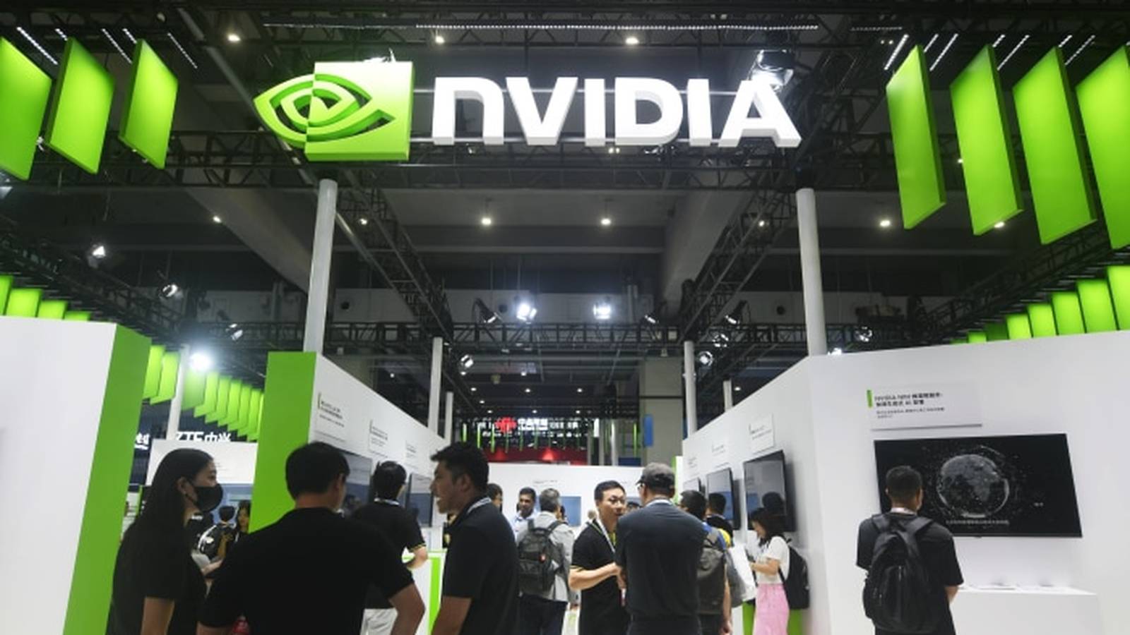 Visitors walking through a bright Nvidia exhibition booth with large green company branding