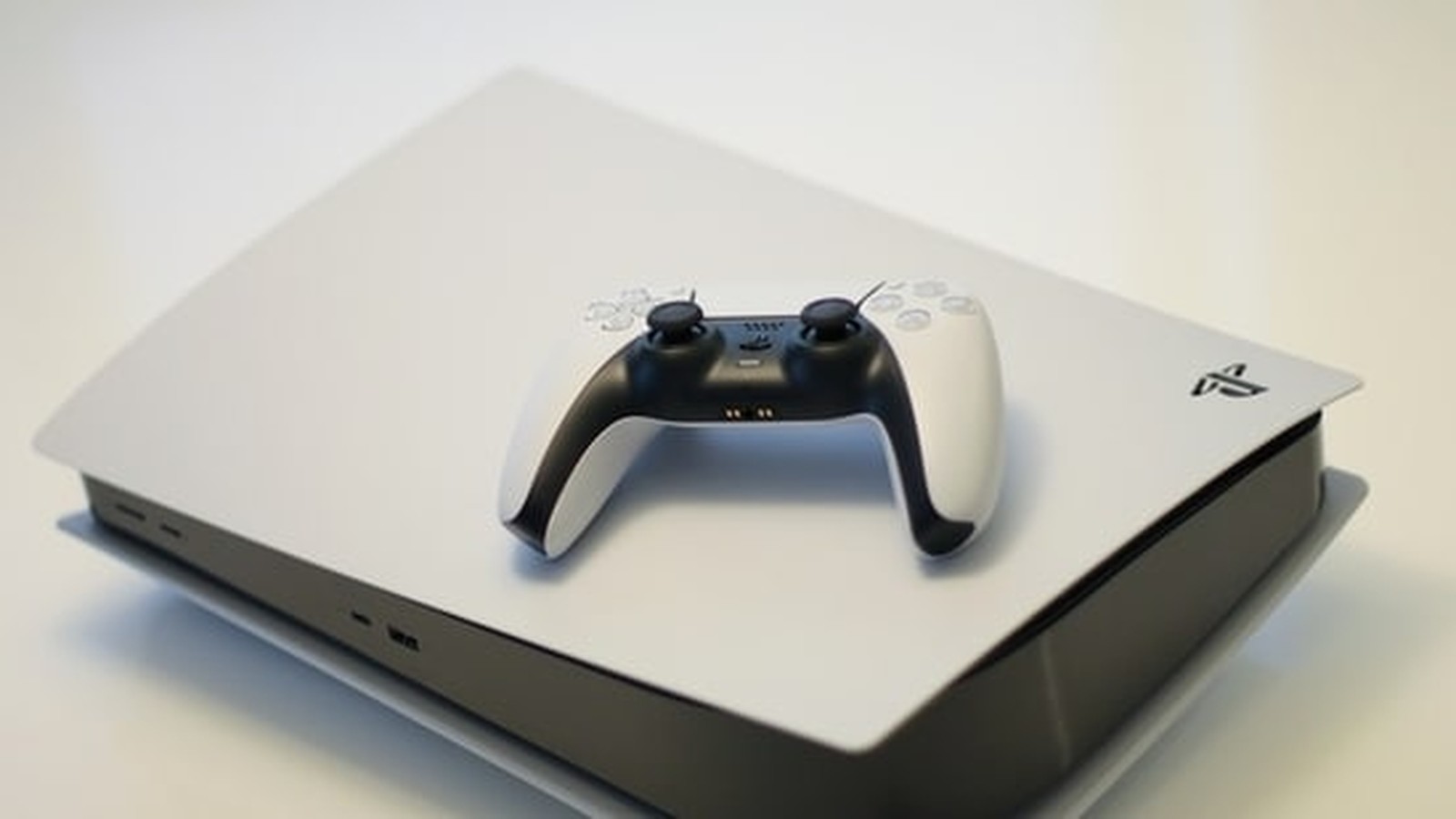 A white PlayStation 5 console with a black and white DualSense controller resting on top