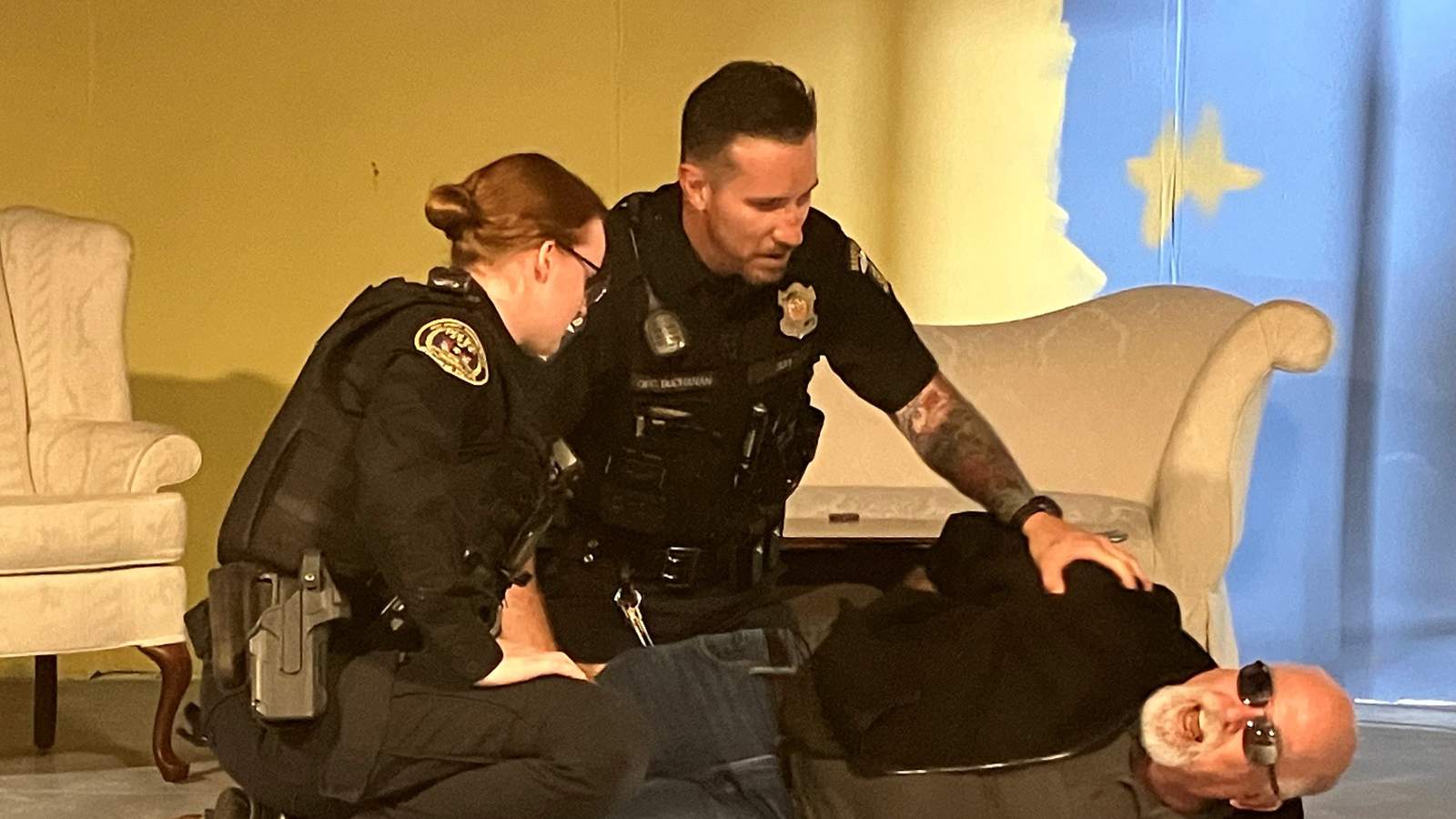 Two police officers kneeling over a man on the floor during intervention