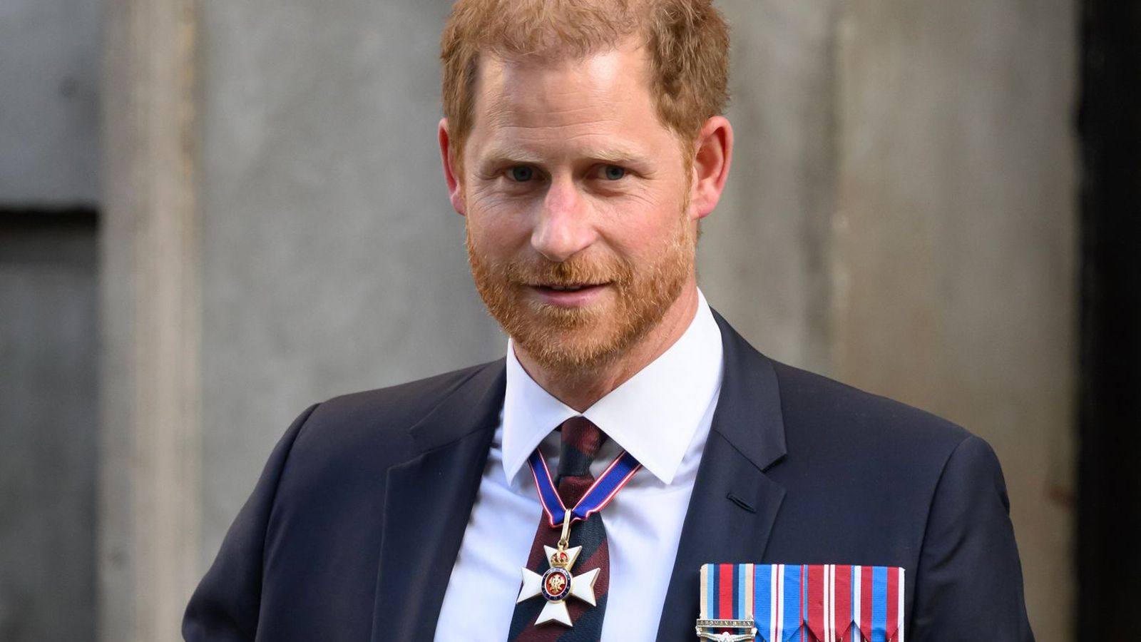 Prince Harry wearing a dark suit with military medals and a neck order