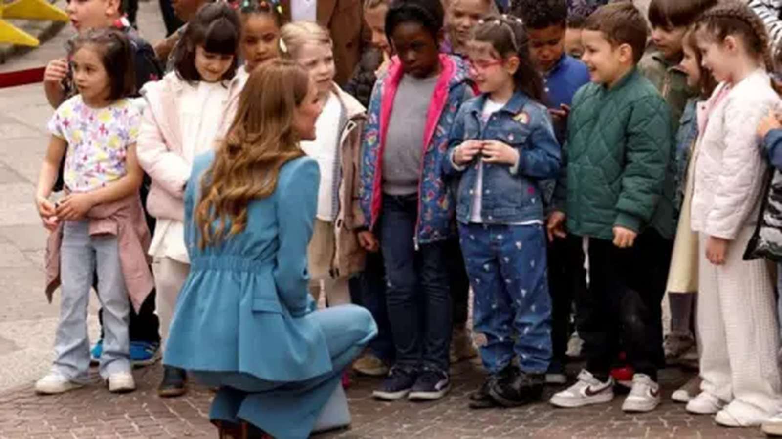 The Princess of Wales kneeling to speak with a group of young children