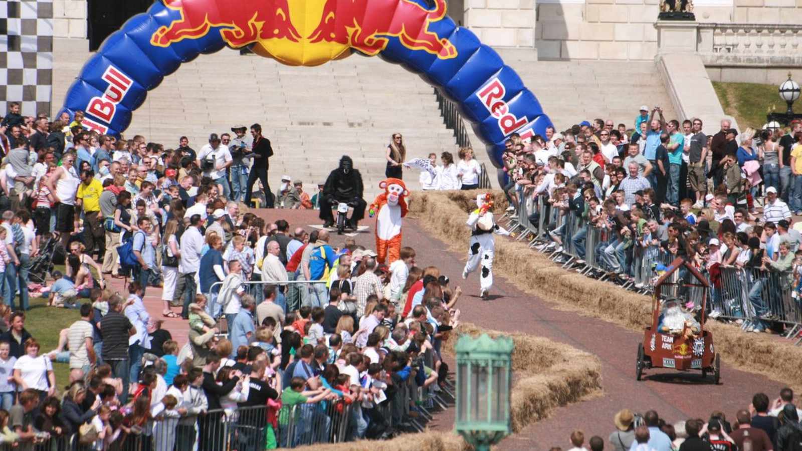 Crowds watch costumed participants racing soapbox cars at the Red Bull event in Belfast
