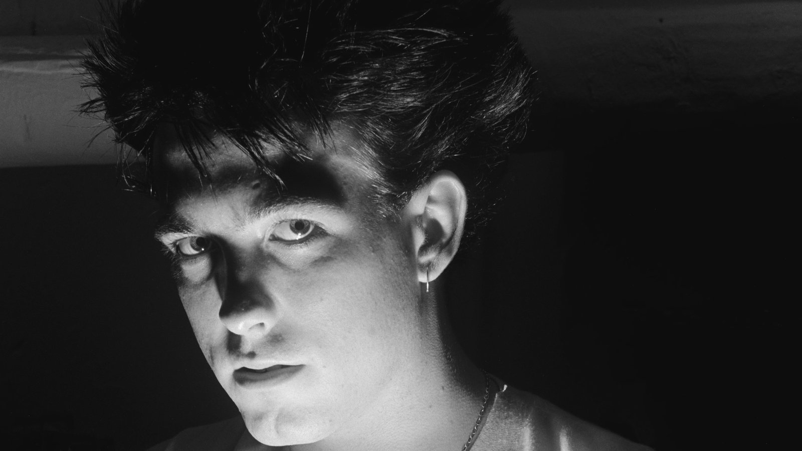 A black and white close-up portrait of musician Robert Smith looking directly forward