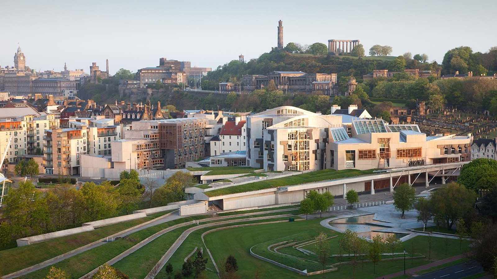 The modern Scottish Parliament building complex situated in Edinburgh with Calton Hill in background