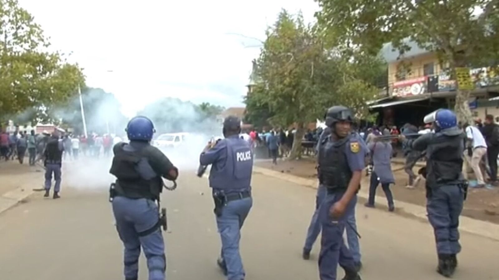 South African police officers in tactical gear responding to a protest with smoke