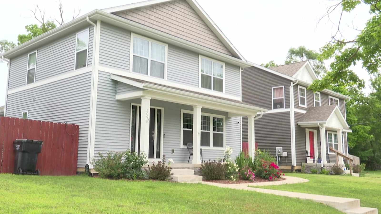Two modern suburban houses with gray siding and front porches on a residential street.